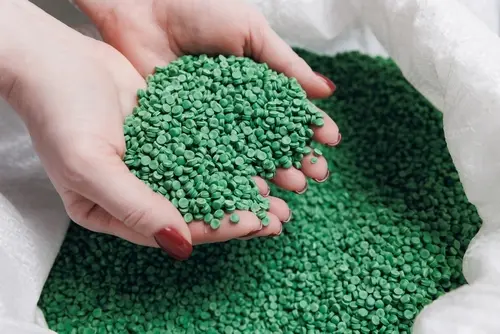woman holding green recycled plastic pellets